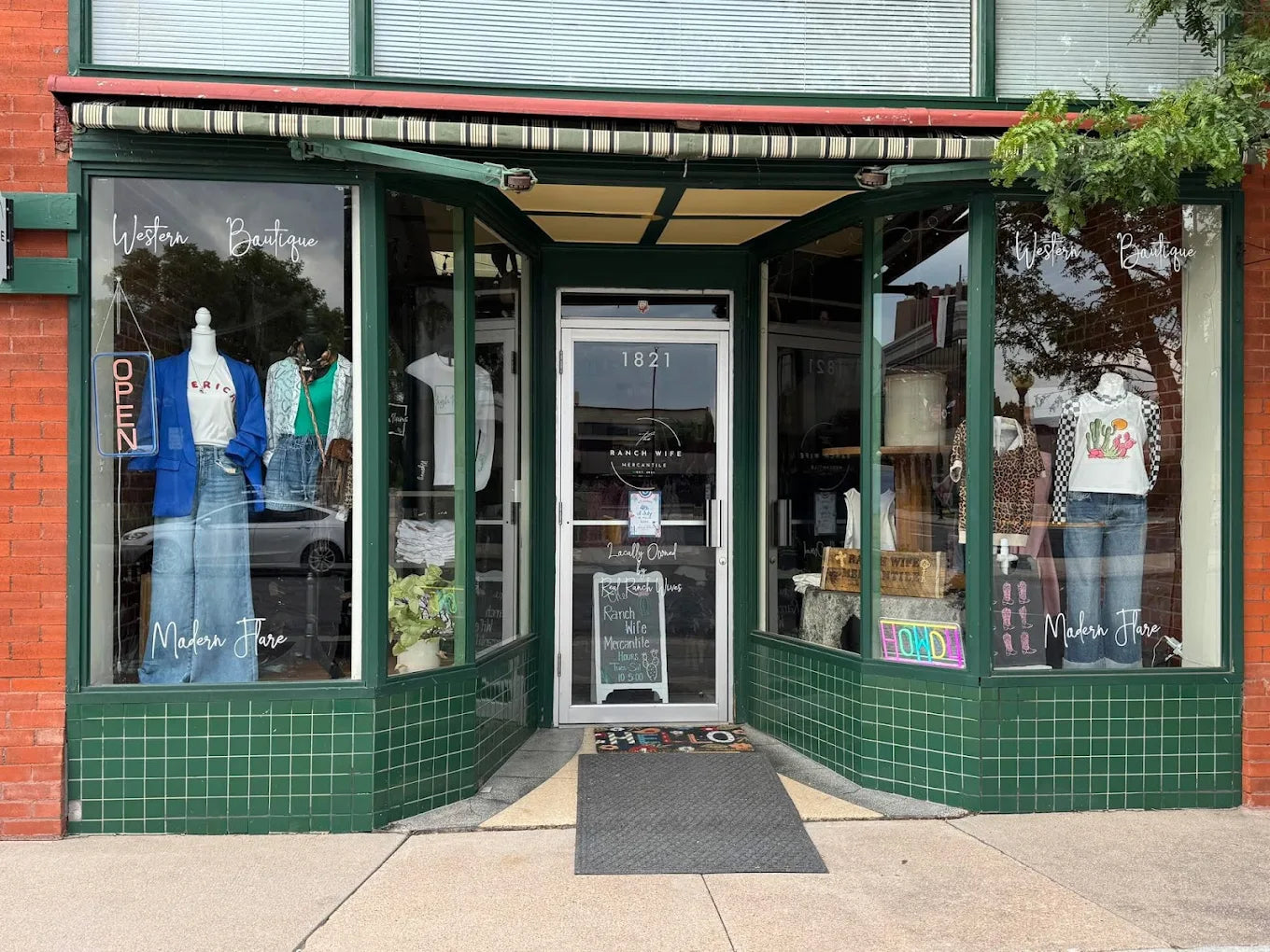 Storefront with green tiled exterior and glass windows displaying clothing.